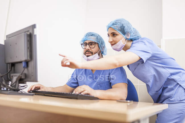 Team von Chirurgen, Mann und Frau, die den Computer vor der Operation benutzen und die Details festlegen — Stockfoto