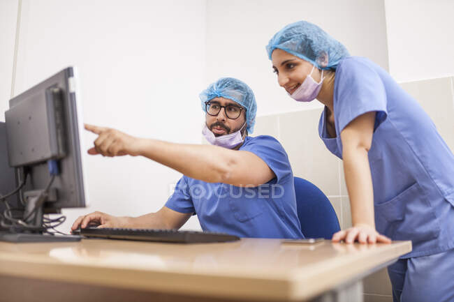 Équipe de chirurgiens, homme et femme utilisant l'ordinateur avant l'opération et commettant les détails — Photo de stock