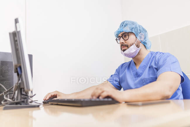 Chirurgo maschio utilizzando il suo computer nel suo ufficio prima dell'intervento chirurgico — Foto stock