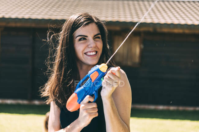 Young woman shooting and splashing with water gun — Stock Photo