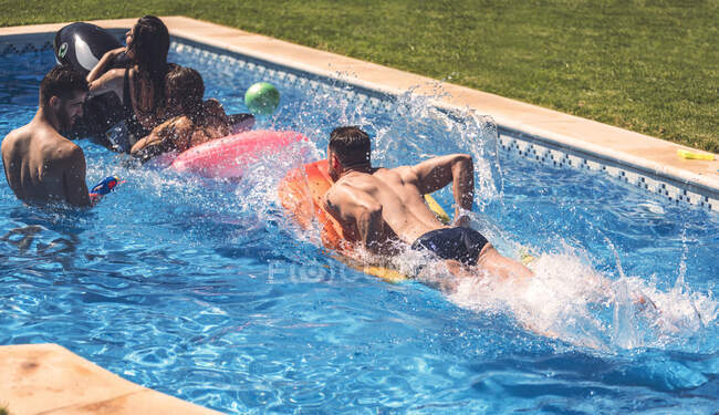 Hombres y mujeres divirtiéndose en la piscina - foto de stock