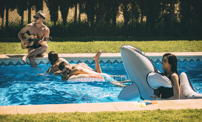 Homens e mulheres relaxando na piscina — Fotografia de Stock