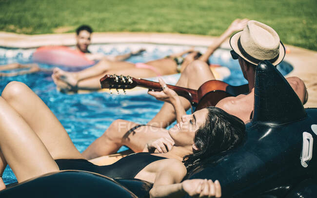 Hombres y mujeres relajándose junto a la piscina - foto de stock