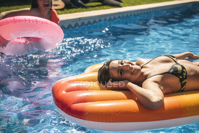 Молодая женщина отдыхает в бассейне с друзьями — стоковое фото