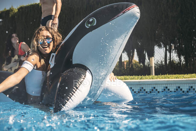 Chica flotando sobre una ballena asesina inflable - foto de stock