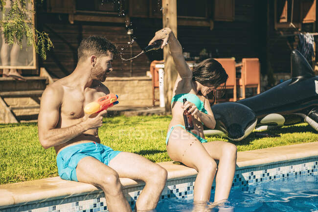 Couple having fun sitting at swimming pool — Stock Photo