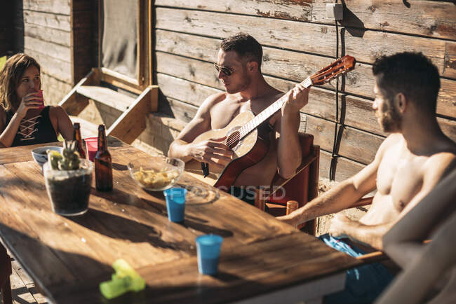 Guy tocando la guitarra para sus amigos - foto de stock