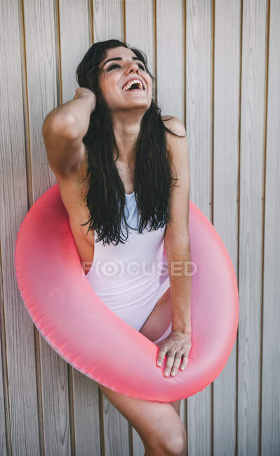 Chica con un anillo de natación posando por cerca de madera blanca - foto de stock