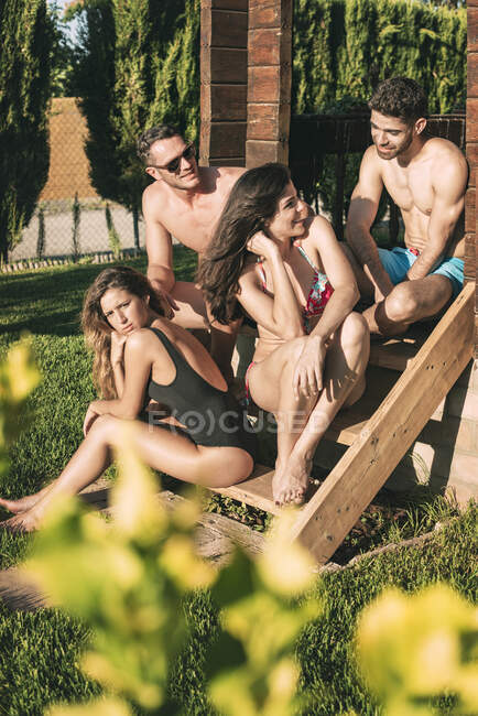 Four friends sitting on stairs on sunshine — Stock Photo