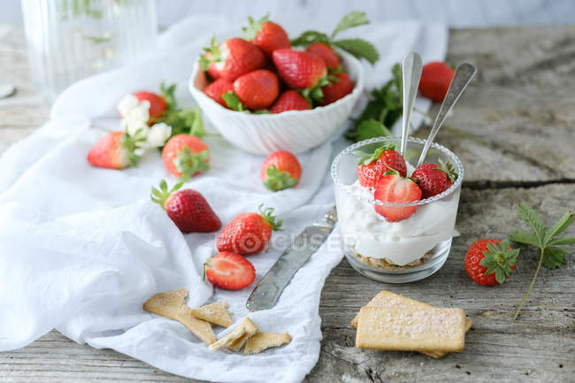Creamy sweet dessert with fresh juicy strawberries served in glass on rustic wooden table with biscuits — Stock Photo