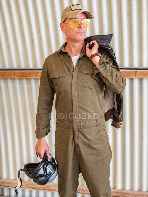 Selbstbewusster Pilot steht im Hangar und hält Helm — Stockfoto