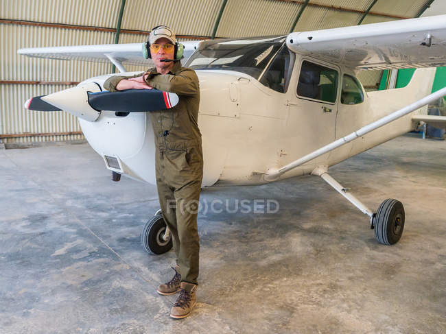 Портрет впевненого пілота, що стоїть біля ретро площини в ангарі — стокове фото