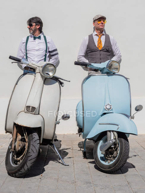 Sonhador hipsters de meia-idade em roupas da moda com retro motos inclinadas na parede no dia ensolarado — Fotografia de Stock