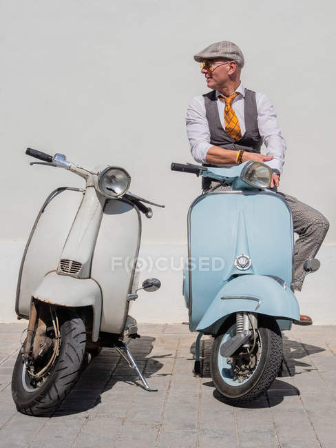 Positivo hipster di mezza età in abiti eleganti con moto retrò che distolgono lo sguardo nella giornata di sole — Foto stock