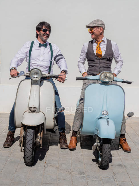 Hipsters positivos de meia-idade em roupas elegantes com motos retro olhando uns para os outros em dia ensolarado — Fotografia de Stock