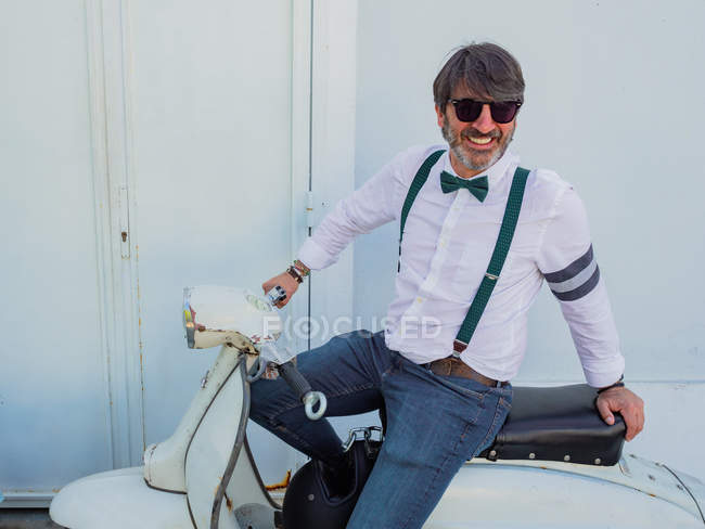 Positiver Hipster mittleren Alters in eleganter Kleidung mit Retro-Motorrad bei sonnigem Wetter — Stockfoto