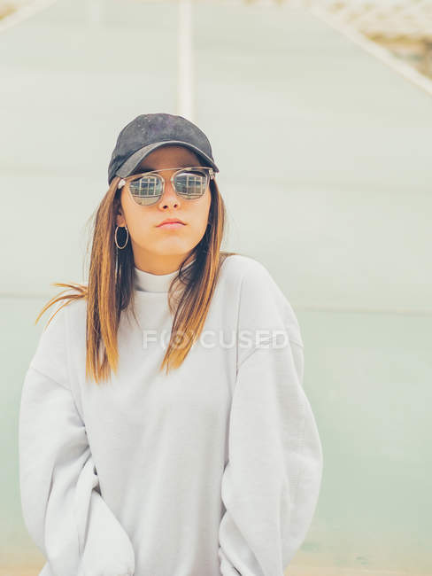 Giovane hipster femminile moderno in abiti casual sullo sfondo della parete geometrica guardando la fotocamera — Foto stock