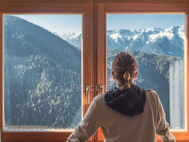 Анонимная женщина смотрит в горы из окна — стоковое фото