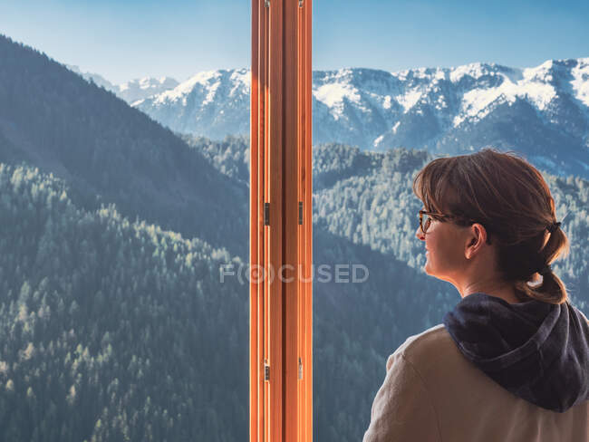 Анонімна жінка дивиться на гори з вікна — стокове фото