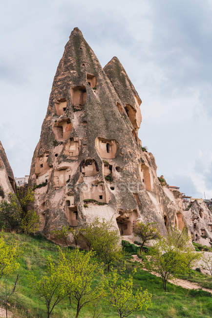 Casas de rocha de cidade velha em montanha áspera contra céu nublado de Capadócia, Turquia — Fotografia de Stock
