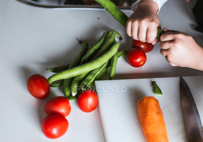 Ragazzo anonimo che sceglie ingredienti per preparare un'insalata sana in cucina — Foto stock
