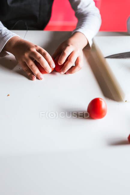 Анонимный мальчик выбирает ингредиенты для приготовления здорового салата на кухне — стоковое фото