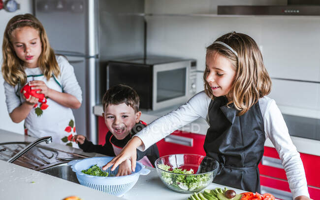 Kleine Mädchen und Jungen beim gemeinsamen Kochen von gesundem Salat in der Küche — Stockfoto