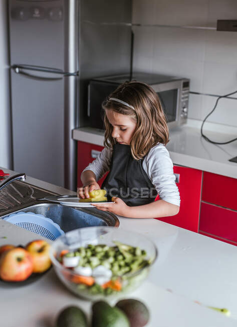 Petite fille utilisant éponge plaque de lavage sur évier dans la cuisine à la maison — Photo de stock