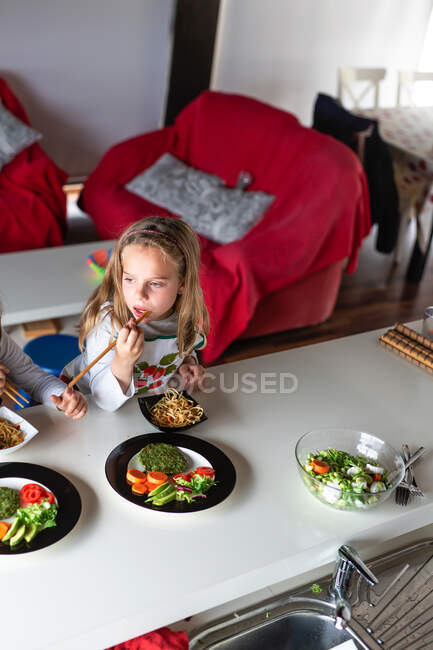 Mädchen isst vegetarische Schnitzel und Gemüse, während sie zu Hause am Tisch sitzt — Stockfoto