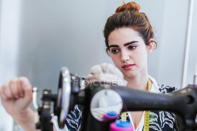 Teenage girl student practicing sewing on modern machine in cozy workshop — Stock Photo