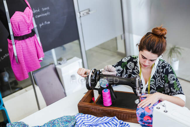 Adolescente estudiante practicando costura en la máquina moderna en acogedor taller - foto de stock