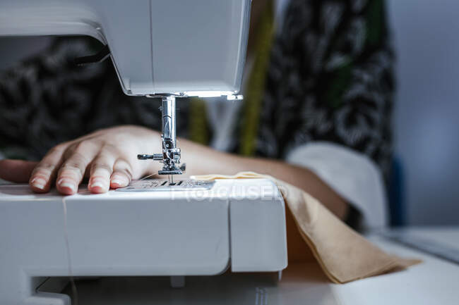 Студентка-подросток практикует шитье на современной машине в уютной мастерской — стоковое фото