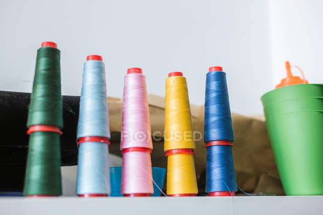 Carretes de hilos en la máquina de coser moderna en acogedor taller - foto de stock