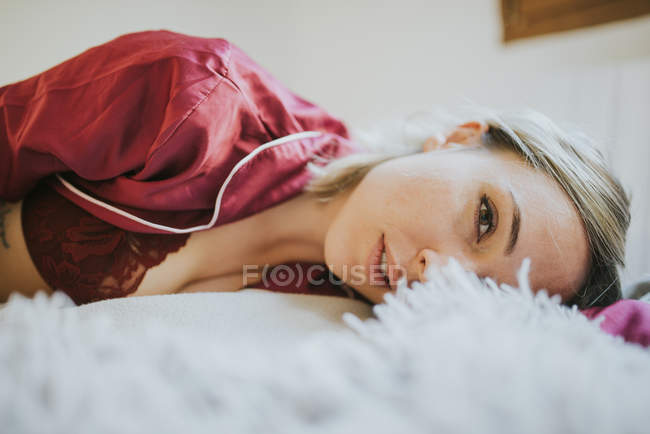 Sensuelle jeune jolie femme en pyjama souriant sur le lit dans la chambre — Photo de stock