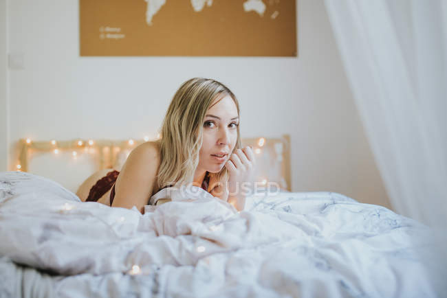 Jeune femme séduisante en sous-vêtements couchée au lit le matin — Photo de stock