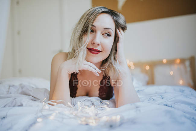 Jeune femme séduisante en sous-vêtements couchée au lit — Photo de stock