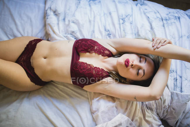 Joven mujer seductora en ropa interior acostada en la cama por la mañana - foto de stock
