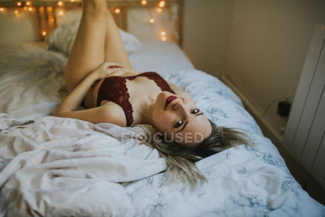 Молодая соблазнительная женщина в нижнем белье лежит в постели с огнями — стоковое фото