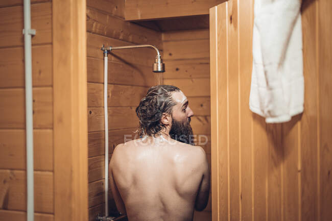 Uomo che si fa la doccia nel bagno in legno — Foto stock