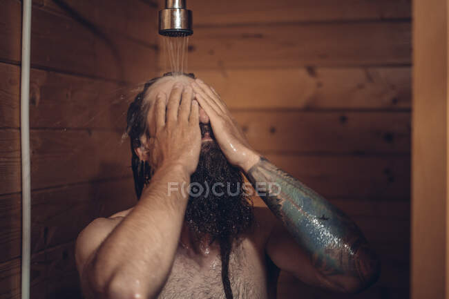 Мужчина принимает душ в деревянной ванной — стоковое фото