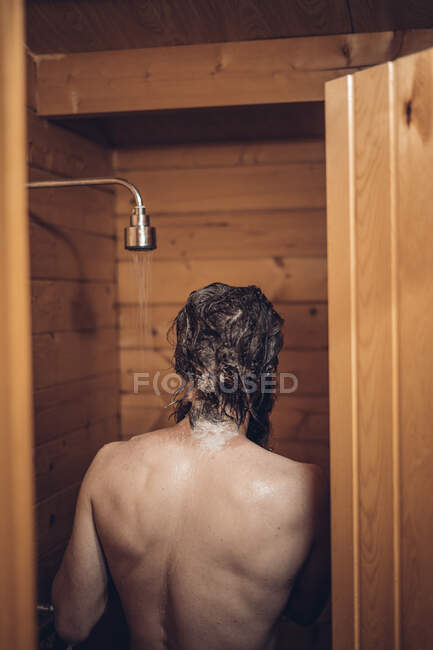 Man taking shower in wooden bathroom — Stock Photo
