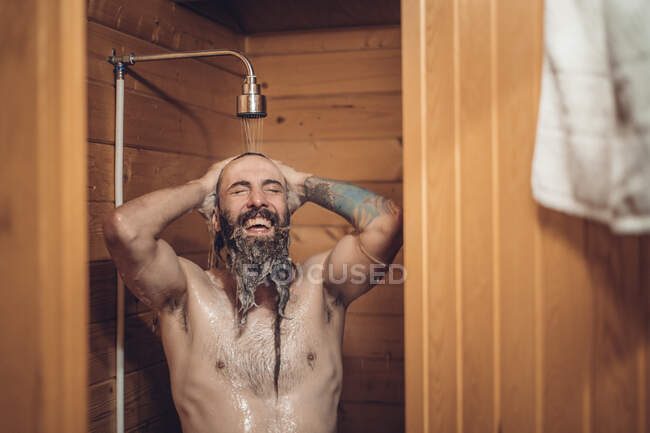 Uomo che si fa la doccia nel bagno in legno — Foto stock
