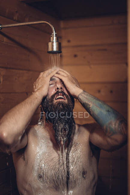 Hombre tomando ducha en baño de madera - foto de stock
