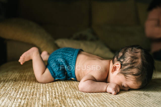 Bonito bebê recém-nascido inocente nas costas deitado no sofá em casa — Fotografia de Stock