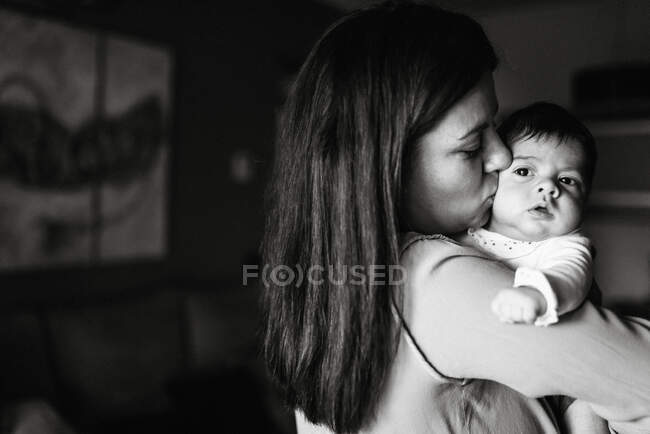 Back view brunette mom hugging cute little baby looking away at home — Stock Photo