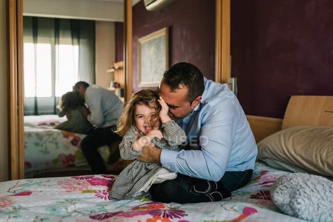 Papá divirtiéndose con la hija feliz mientras está acostado en la cama - foto de stock