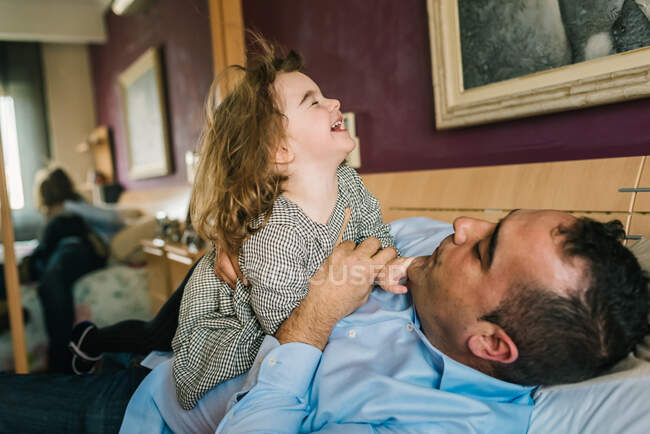 Papà avendo divertimento con felice figlia holding su mani mentre sdraiato su letto — Foto stock