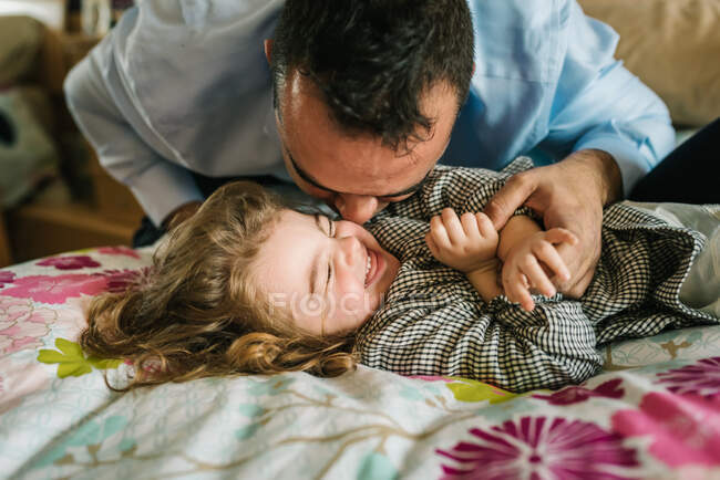 Pai se divertindo com a filha feliz enquanto deitado na cama — Fotografia de Stock