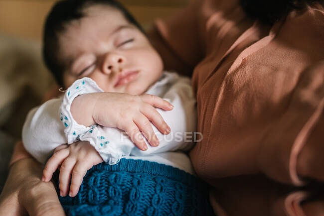 Back view unrecognizable brunette mom hugging cute little baby looking away at home — Stock Photo