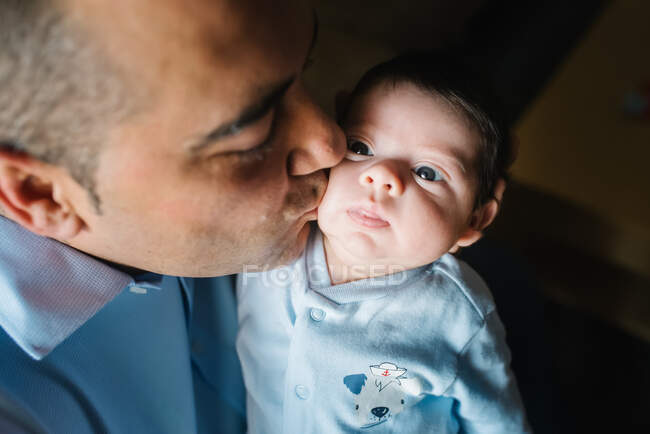 Отец обнимает и целует миленького малыша дома — стоковое фото